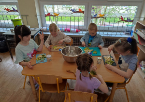 Piątka dzieci podczas krojenia awokado i banana