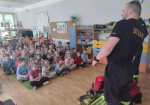 Dzieci słuchają jak strażacy opowiadają o swojej pracy