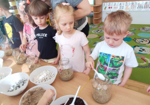 Dzieci nasypują piasek do słoika