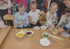 Dzieci podczas przygotowywania szaszłyków owocowych