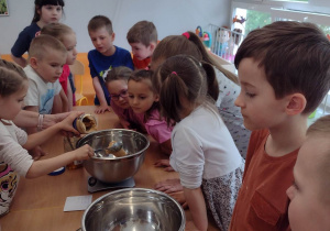 Dzieci obserwują jak dziewczynka dodaje masło orzechowe