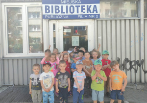 Dzieci stoją przed wejściem do Miejskiej Biblioteki Publicznej przy ulicy Łaskiej