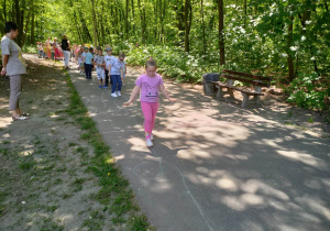 Dzieci idą po narysowanej ścieżce kredą w parku