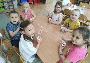 Dzieci jedzą lody w kubeczkach
