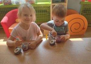 Dwoje dzieci miesza kolorowe kulki w kleju z brokatem