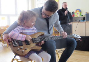 dziewczynka próbuje zagrać na gitarze elektrycznej