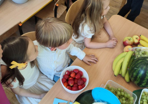 Dzieci siedzą przy stole z owocami
