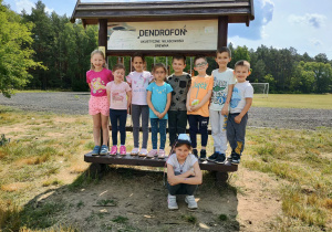 Dzieci stoją przy tablicy edukacyjnej o dendrofonie
