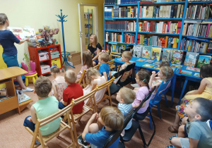 Przedszkolaki słuchają książki czytanej przez panią bibliotekarkę