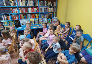 Dzieci siedzą na krzesełkach w czytelni
