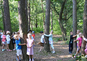 Dzieci z grupy Myszek przytulają się do drzew w parku