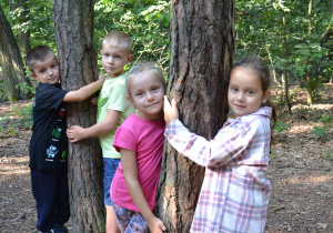 Czworo dzieci przytula się do drzew