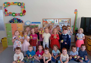 Dzieci z grupy II stoją razem i pokazują soczki otrzymane z okazji Dnia Przedszkolaka