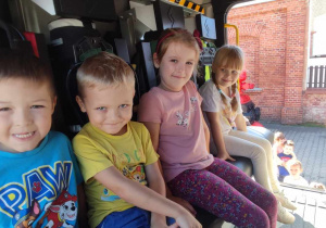 Czwórka dzieci siedzi w wozie strażackim