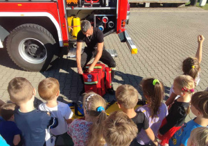 Dzieci oglądają plecak z wyposażeniem ratunkowym strażaka