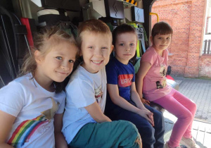 Czworo dzieci siedzi w samochodzie strażackim