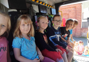 Sześcioro dzieci siedzi w samochodzie strażackim
