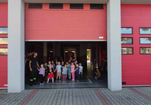 Dzieci stoją w bramie wyjazdowej samochodu strażackiego