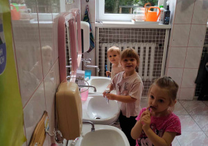 Troje dzieci myje ząbki