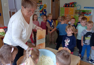Nauczycielka pokazuje dzieciom poszatkowaną kapustę w misce