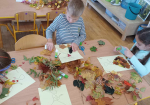 Troje dzieci przykleja liście na szablon sukienki