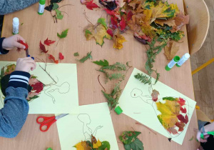 Pięcioro dzieci przykleja liście na sukienkę pani jesieni