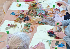 Czworo dzieci przykleja liście na szablon sukienki
