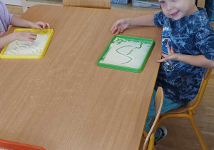 Chłopiec pokazuje literkę A napisaną na kaszy