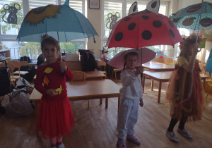 Trzy dziewczynki trzymają parasolki do piosenki o deszczu