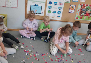 Dzieci nakładają gumki na papierowe rolki