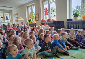 Przedszkolaki siedzą na dywanie i oglądają bajkę o Neciku