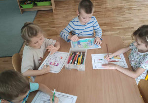 Czworo dzieci z grupy III kolorują obrazki o dobrym zachowaniu