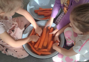 Trzy dziewczynki myją marchewkę