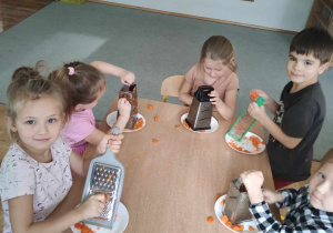 Przedszkolaki ścierają marchewkę na tarce