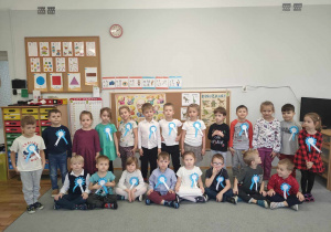 Przedszkolaki z grupy III z niebieskimi kotylionami przyczepionymi do ubrań