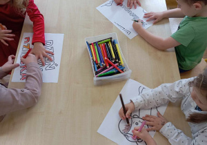 Szóstka dzieci koloruje części plakatu o prawach dziecka