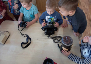 Chłopcy oglądają stare urządzenia przy stoliku