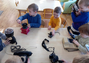 Chłopcy oglądają urządzenia elektryczne przy stoliku