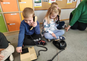 Dwoje dzieci bawi się starymi telefonami