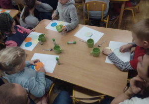 Dzieci siedzą przy stoliku z kolorowymi kółkami
