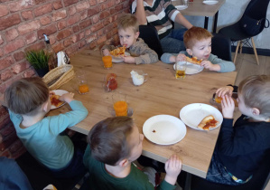 Pięciu chłopców podczas jedzenia pizzy