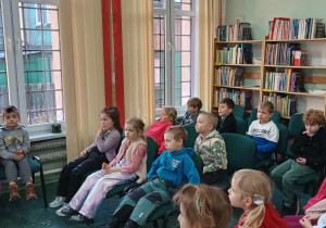 Dzieci siedzą na krzesełkach w bibliotece