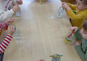 Przedszkolaki nasypują soli do słoików
