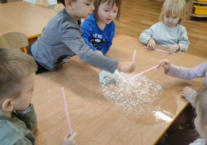 Dzieci wykonują bańki przez słomkę