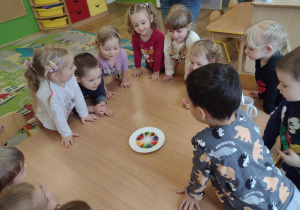 Dzieci obserwują wodę, która barwi się dzięki kolorowym cukierkom