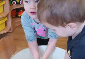 Dwoje dzieci bawi się masą z mąki