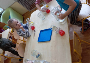 Dzieci nalewają wodę do słoików