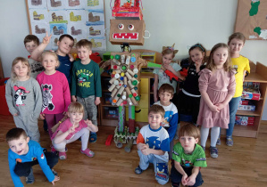 Dzieci z grupy czwartej z robotem wykonanym z pudełek, rolek i korków