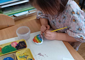 Dziewczynka maluje kamyczek farbami