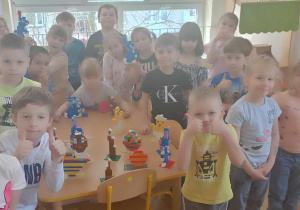 Dzieci z grupy IV stoją przy stoliku, na którym stoją ich budowle z lego